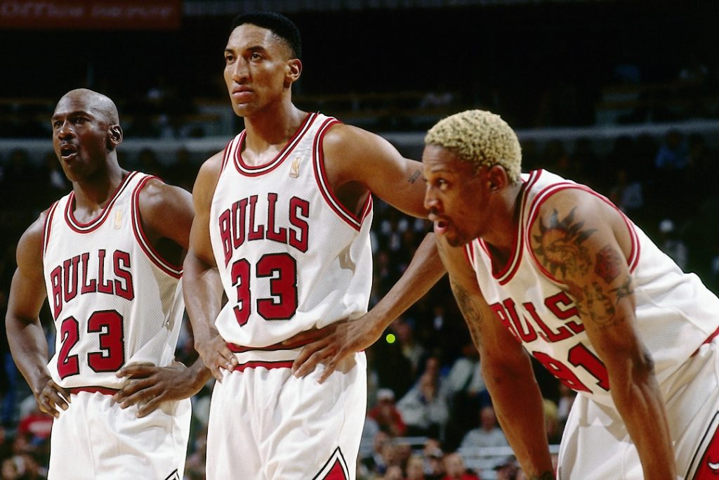 Michael Jordan, Scottie Pippen e Dennis Rodman lado a lado em quadra.