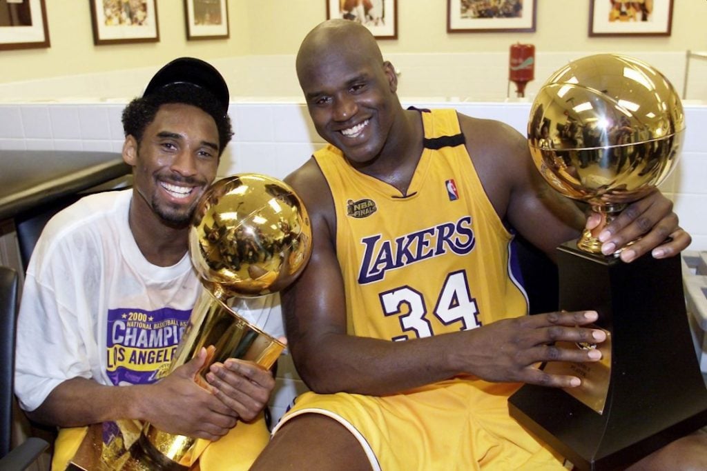 Um jovem Kobe ao lado de Shaq, posando com seus troféus.