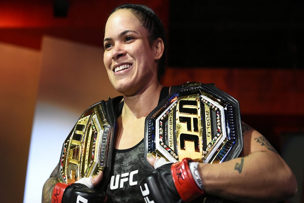 A melhor lutadora do UFC feminino da história, Amanda Nunes, segurando dois cinturões.