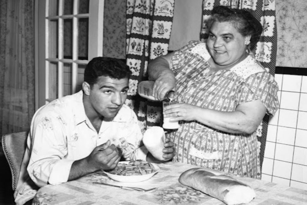 O melhor boxeador da história, Rocky Marciano, comendo sentado à mesa.