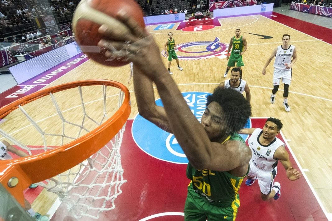 Bruno Caboclo enterrando bola durante o pré-olímpico de basquete para Paris 2024 com a camisa da seleção brasileira.