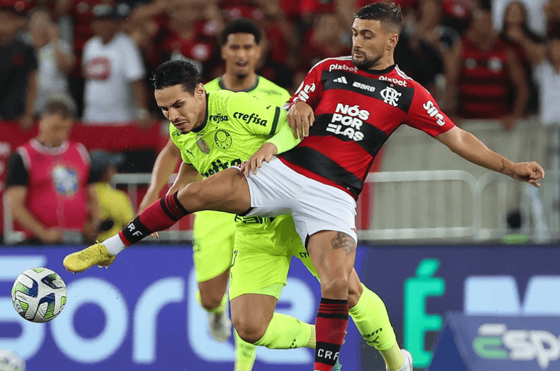 Raphael Veiga e Arrascaeta em disputa de bola durante partida entre Flamengo e Palmeiras, pelo Brasileirão.