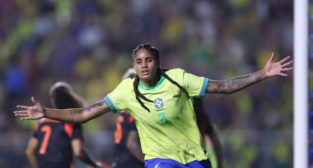 Jogadora da seleção brasileira feminina de futebol comemora gol em amistoso, de braços abertos.