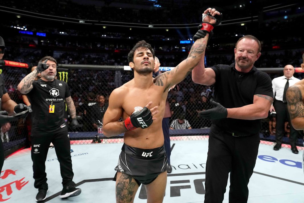 Alexandre Pantoja tem o braço levantado para comemorar vitória no octógono do UFC.