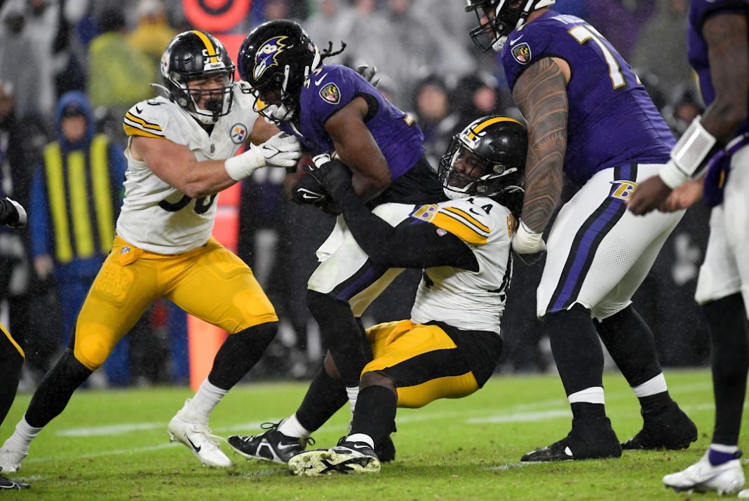 Lamar Jackson, quarterback do Baltimore Ravens, corre com a bola entre os defensores do Pittsburgh Steelers, na NFL.