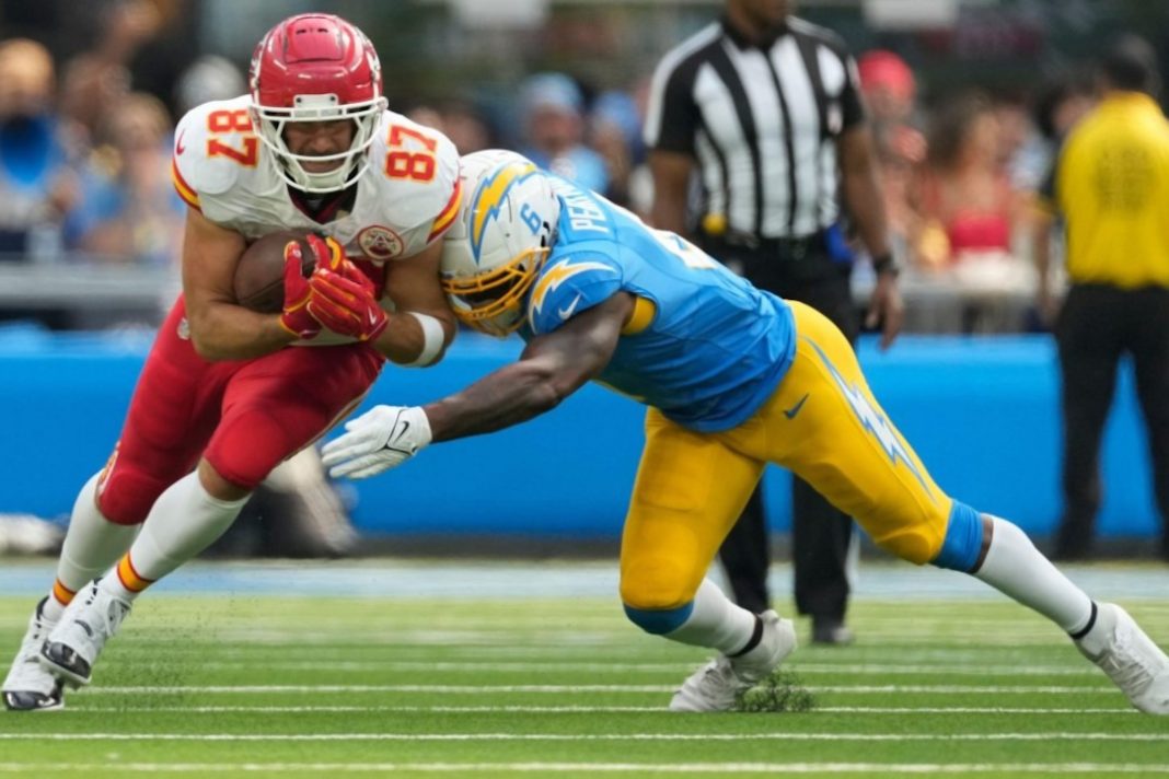 Travis Kelce, do Kansas City Chiefs, sofre tackle de defensor do Los Angeles Chargers em partida da temporada da NFL 2024-25.