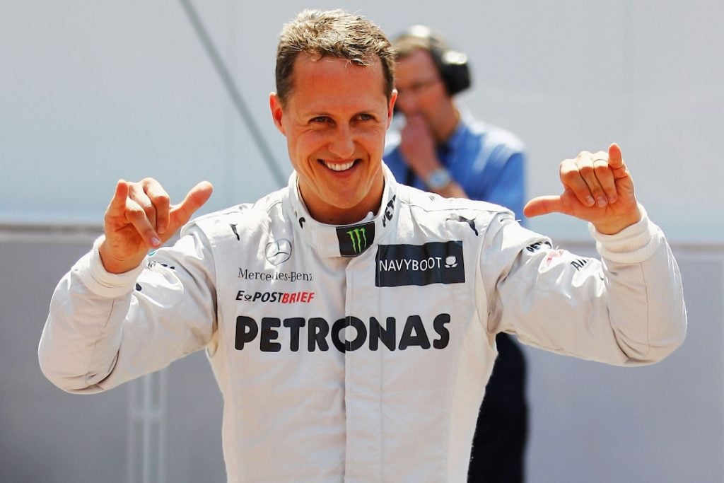 A photo of one of the best F1 drivers Michael Schumacher waving to fans in the pit lane wearing his Mercedes race suit