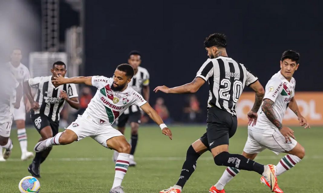 Disputa de bola entre jogadores do Botafogo e do Fluminense durante partida entre os dois clubes cariocas.